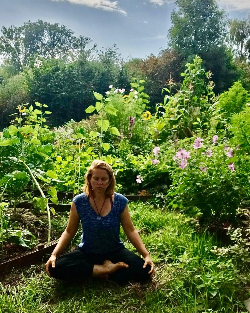 Anne-Catherine Blanpain, professeure de Yoga Parinama — Hatha Raja Yoga à Jodoigne, assise en méditation dans un jardin